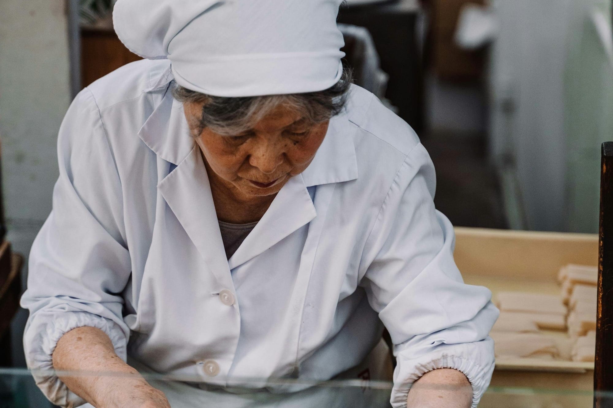 man in white dress shirt and white hat sitting on brown wooden bench
