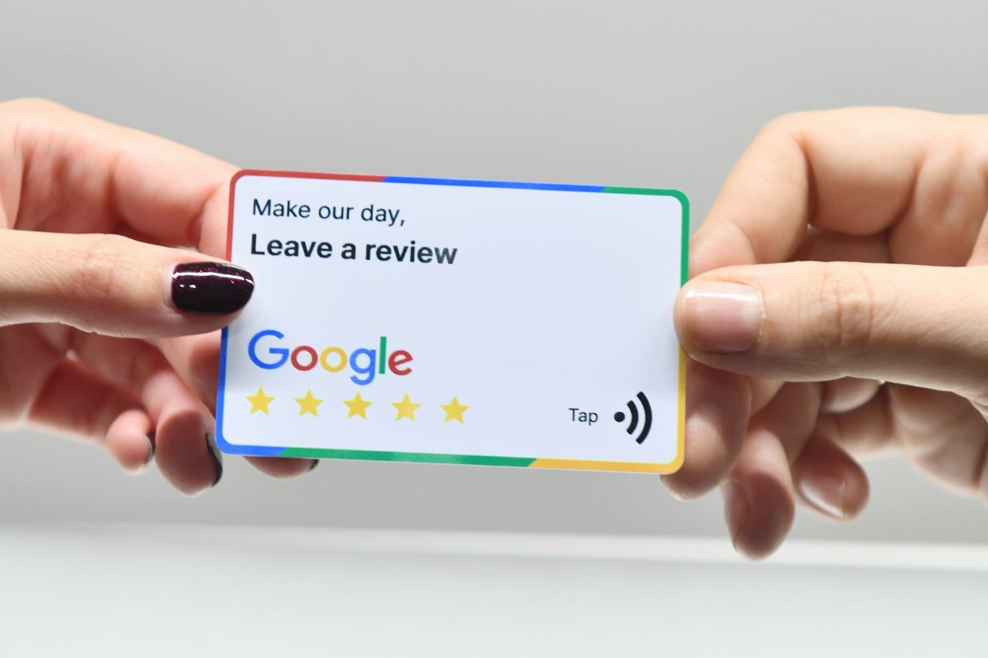 two hands holding a google credit card in front of an apple logo